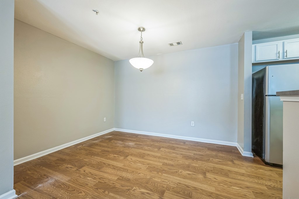 A kitchen area with a refrigerator and wooden flooring.