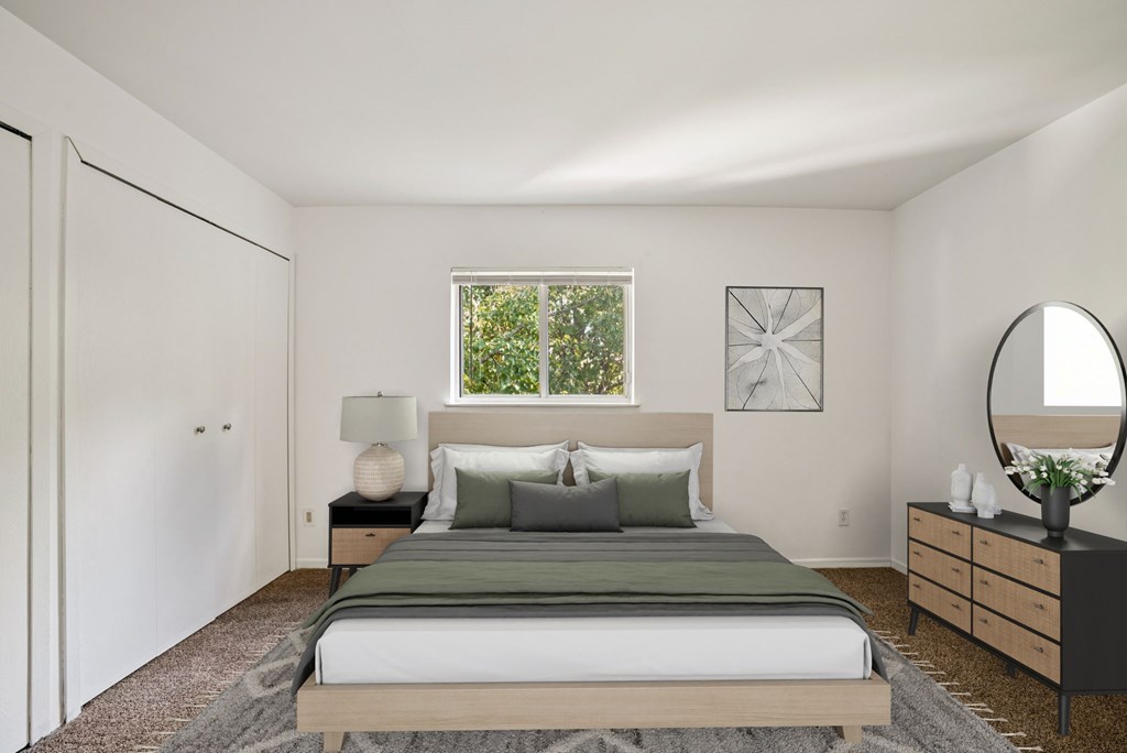 A bedroom with a bed, nightstand, and a mirror.