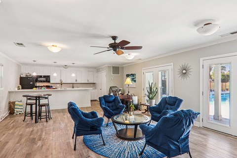 A living room with blue chairs and a ceiling fan.