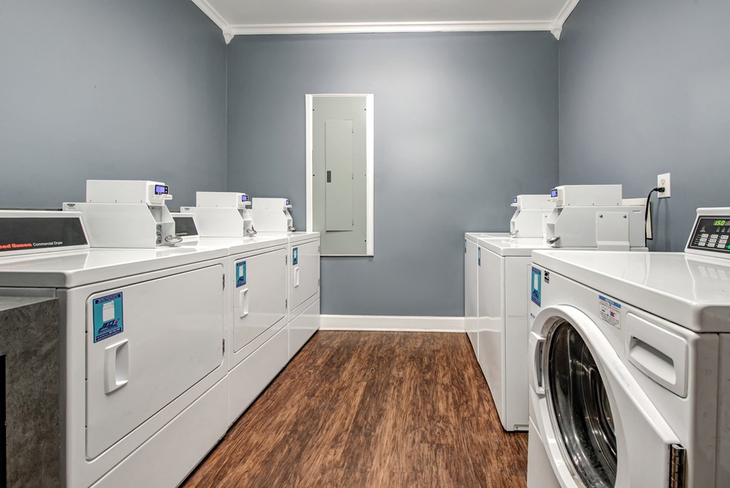 a laundry room with washers and dryers and a row of washing machines