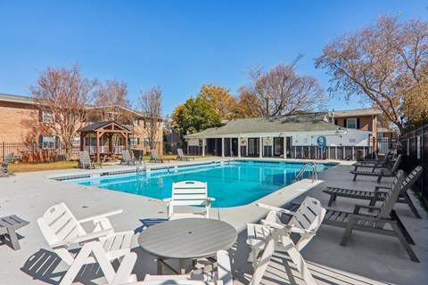 A pool surrounded by chairs and tables.