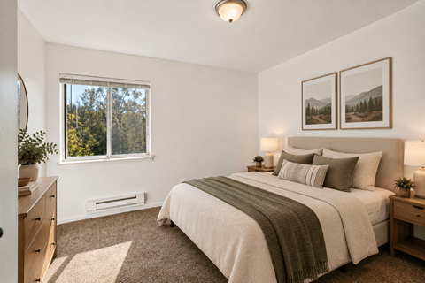 A bedroom with a large bed and a window overlooking trees.