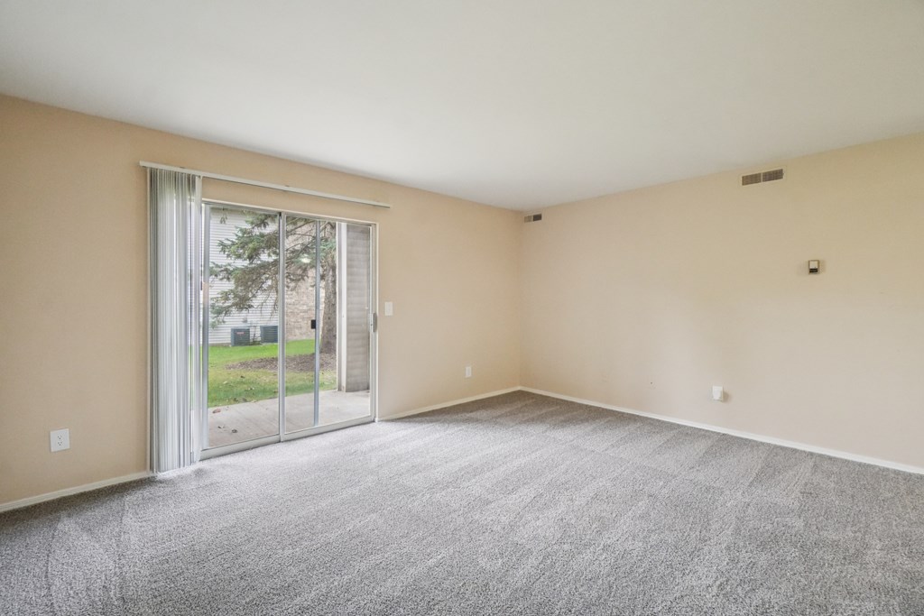 A room with a carpeted floor and sliding glass doors.