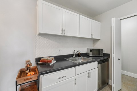 A kitchen with white cabinets and a black countertop.