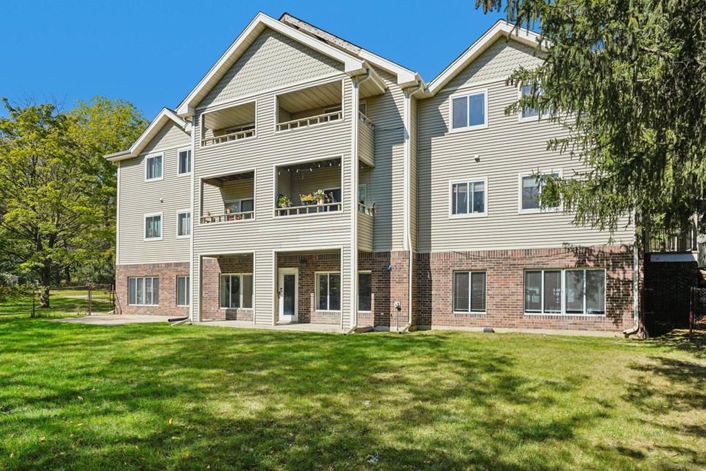 A large apartment building with a green lawn in front.
