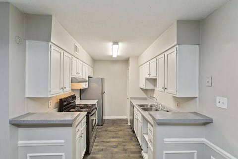 A kitchen with white cabinets and a grey countertop.
