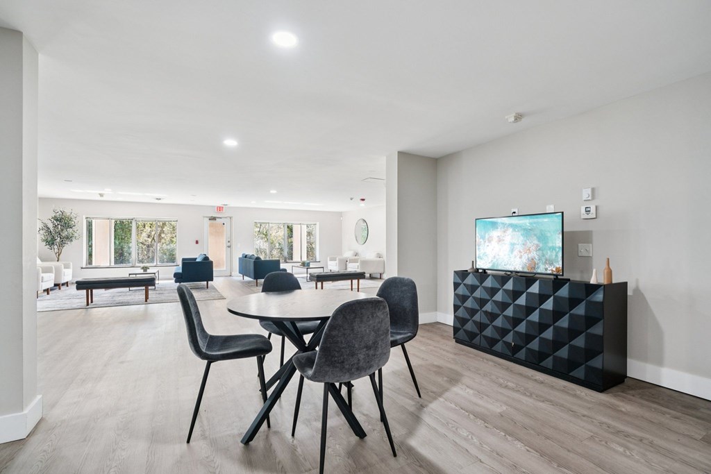 A modern living room with a TV, chairs, and a dining table.