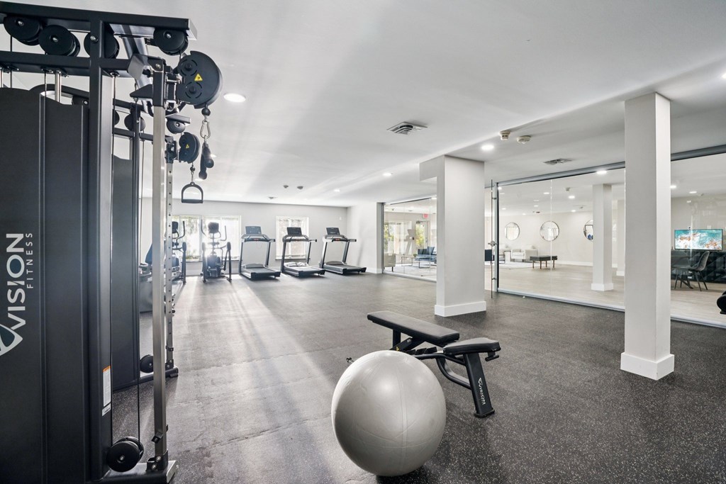 A gym with a variety of equipment including a weight bench and a medicine ball.