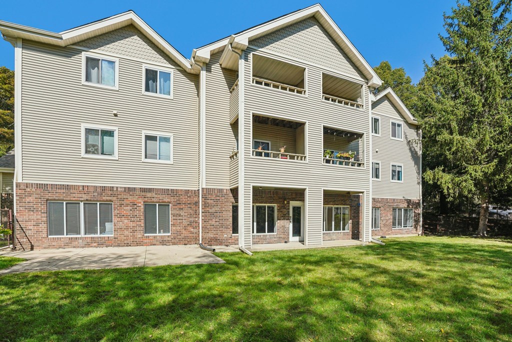 A large apartment building with a green lawn in front.