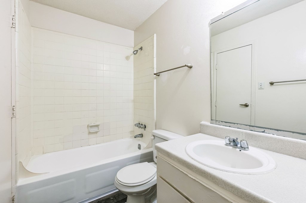 A white bathroom with a toilet, sink, and bathtub.