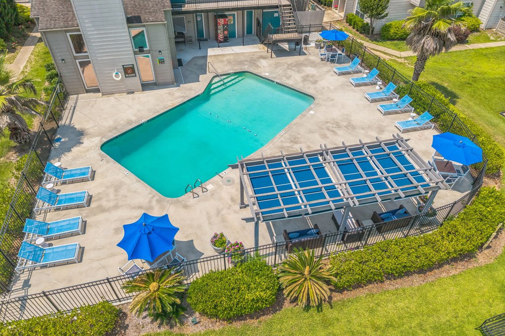A large swimming pool surrounded by sun loungers and umbrellas.
