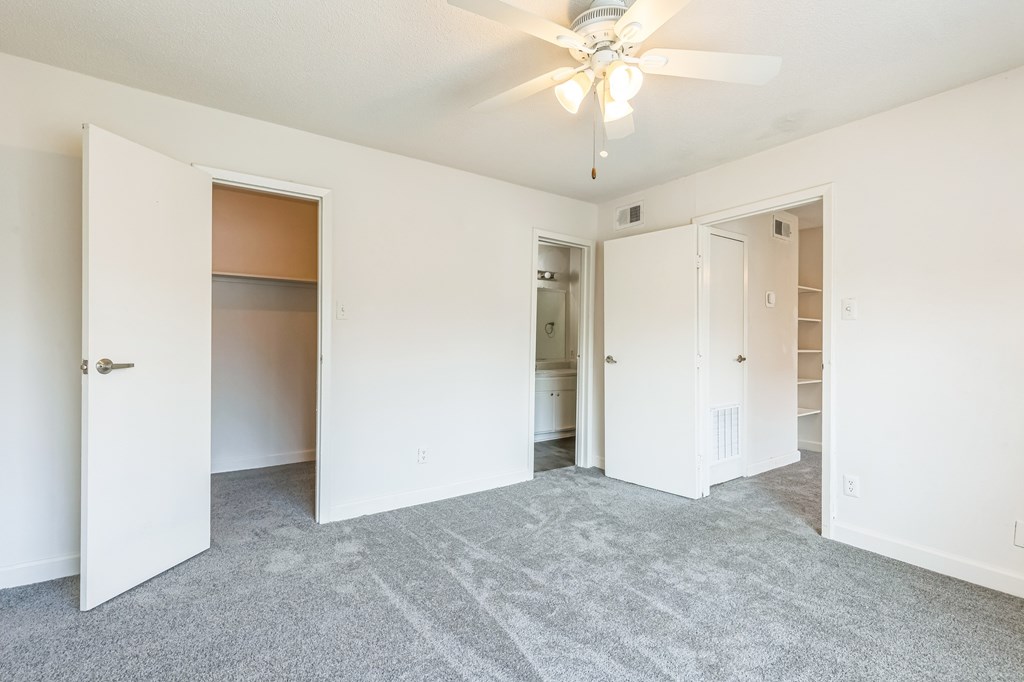 A room with a ceiling fan and carpeted floor.