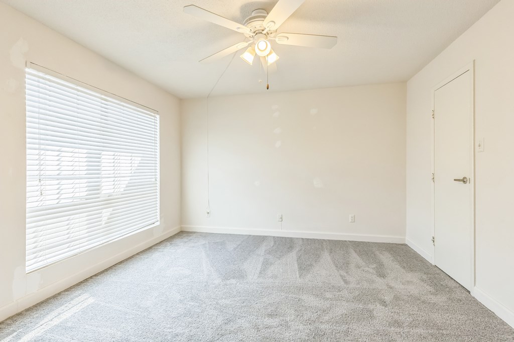 A room with a ceiling fan and carpeted floor.
