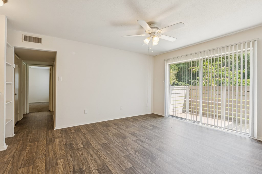 A room with a ceiling fan and sliding glass doors.