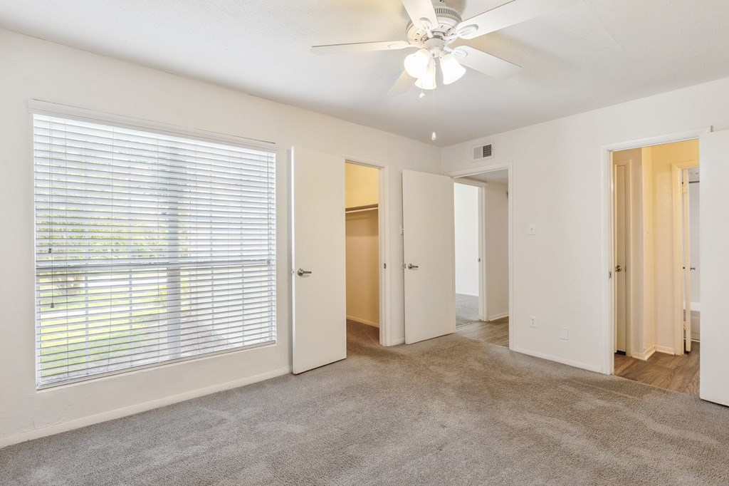 A room with a ceiling fan and carpeted floor.