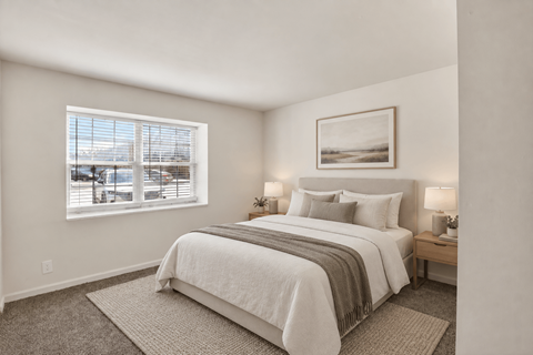 A bedroom with a large bed and a window overlooking a cityscape.