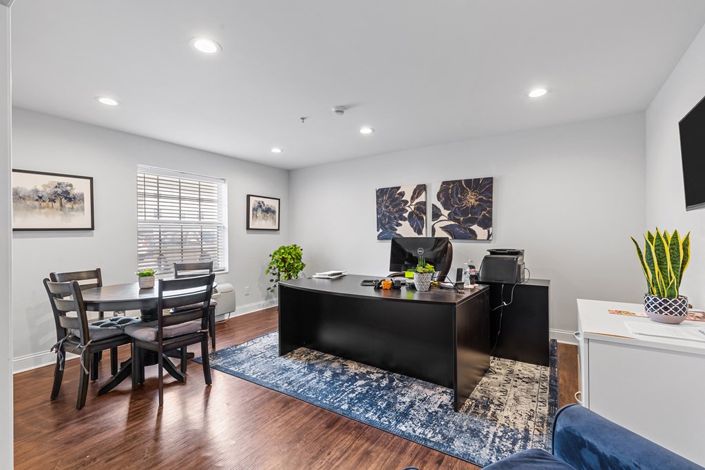 a living room with a desk and a table with chairs