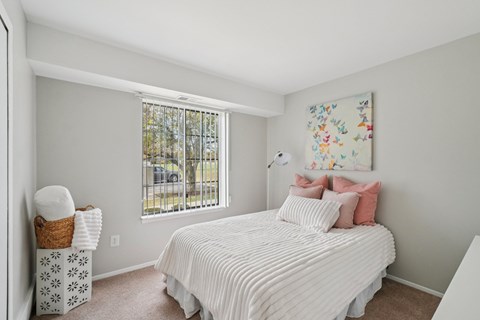 A white bedroom with a large bed and a window.