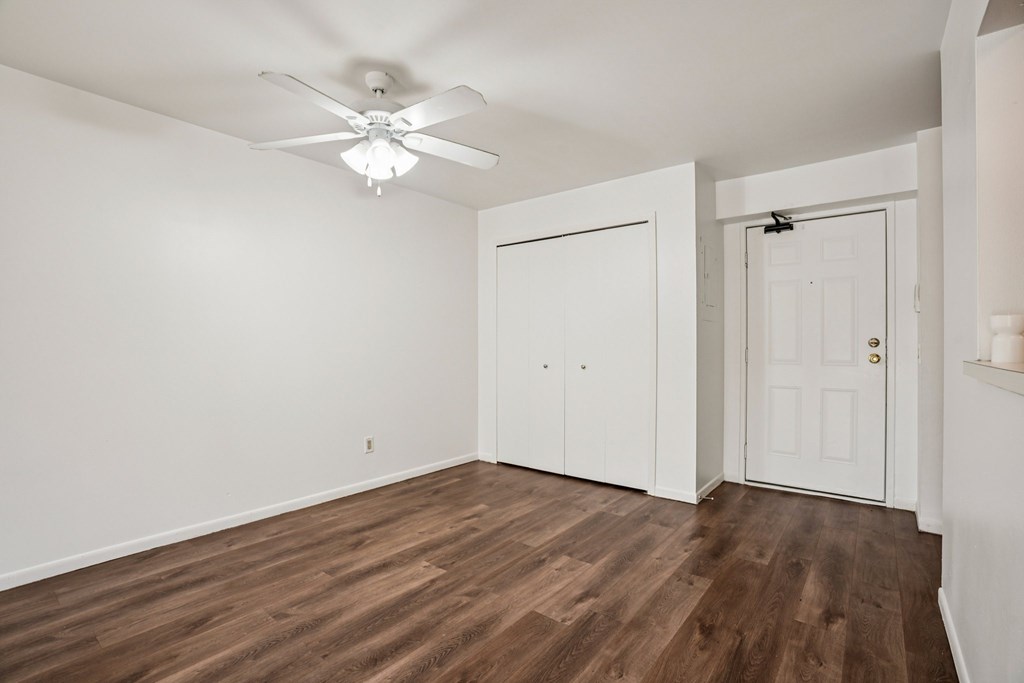 A room with a ceiling fan and wood flooring.