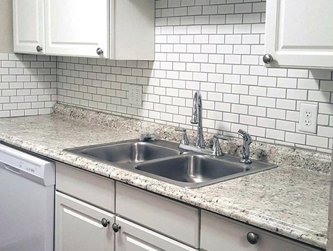 a kitchen with a sink and white tiles