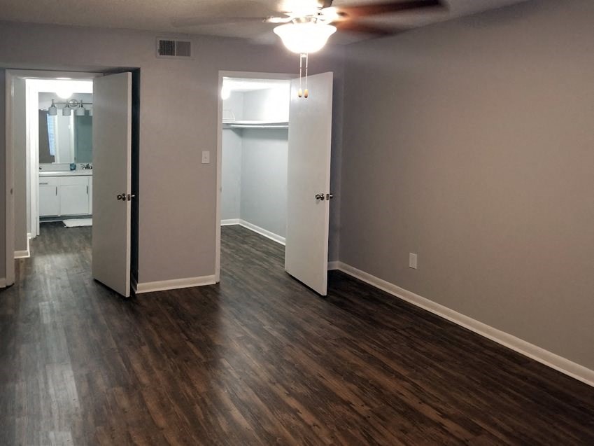 an empty room with hardwood floors and a ceiling fan