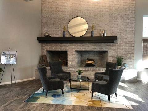 a living room with chairs in front of a brick fireplace