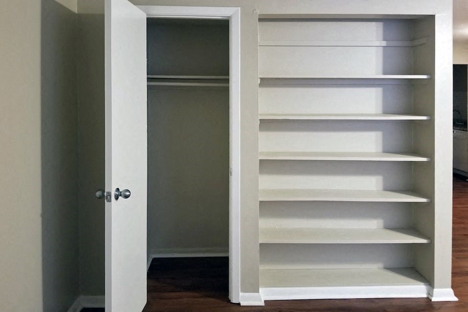 a closet with white shelves and a white door