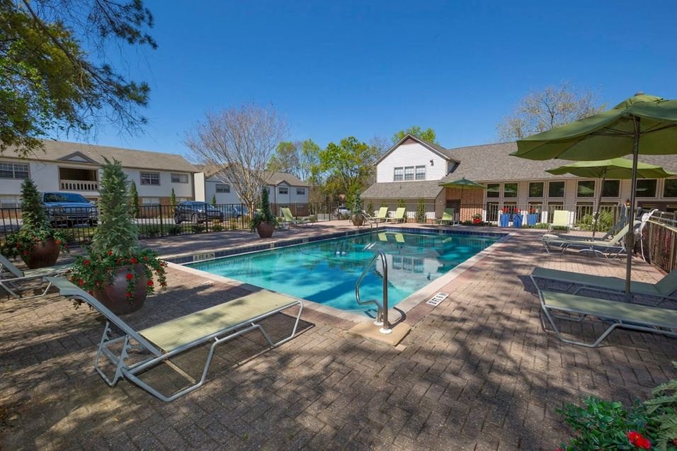a swimming pool with lounge chairs and umbrellas in front of a building