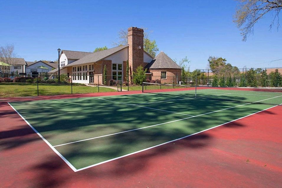 a tennis court with a house in the background