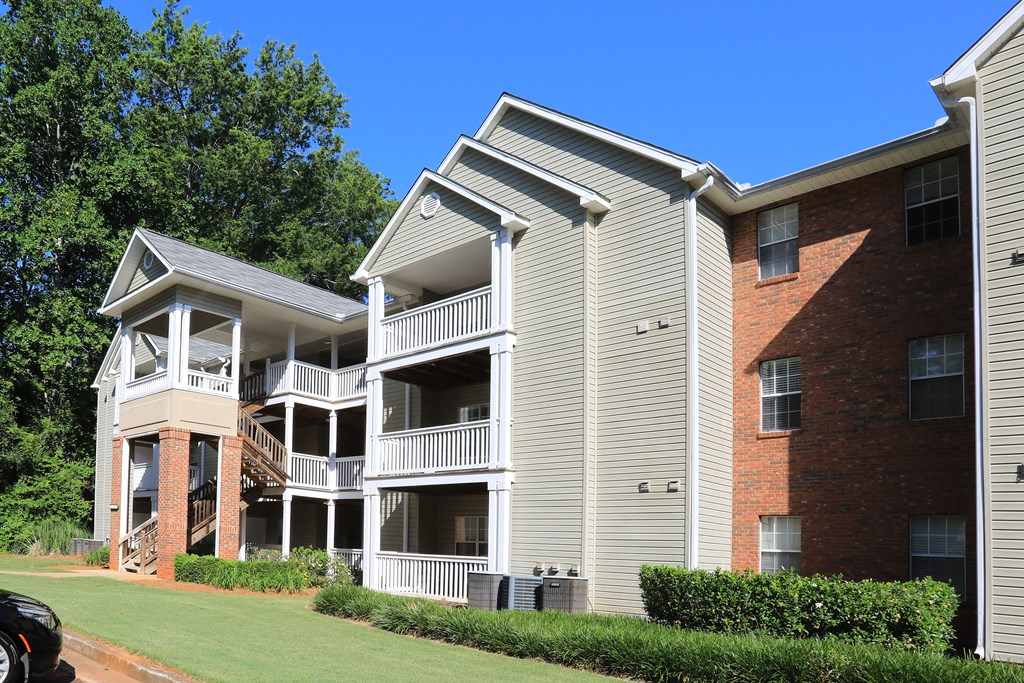 an exterior view of an apartment building with a lawn and trees