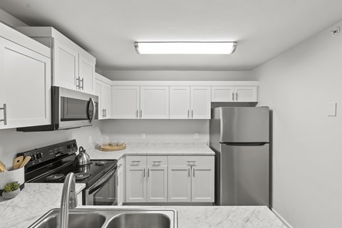 A kitchen with white cabinets and appliances.