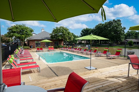 Community pool area with red chairs and green umbrellas at Southwind Apartments in Richland, MS.