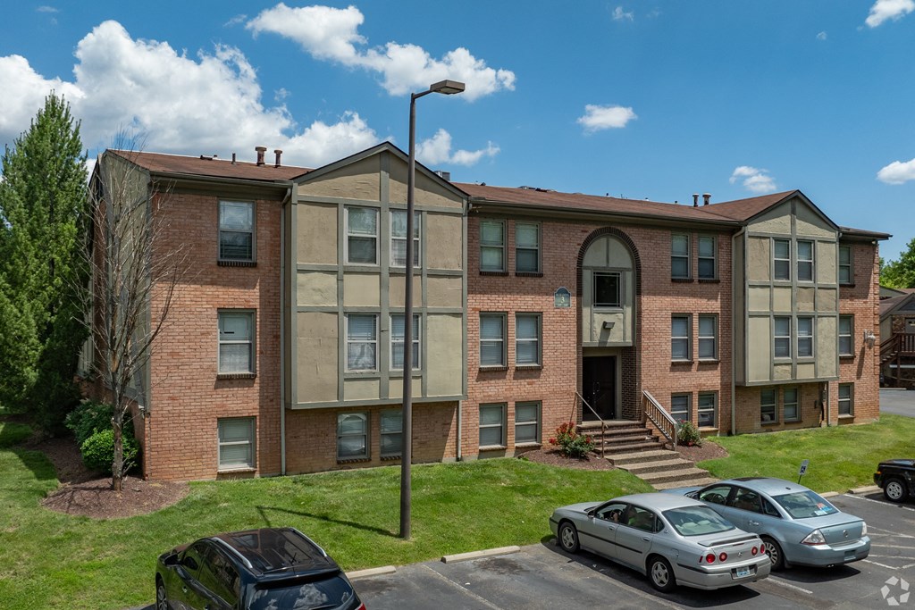 a large brick apartment building with cars parked outside