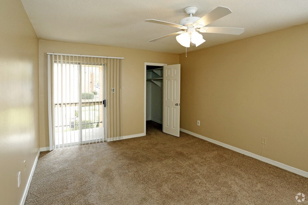 an empty living room with a ceiling fan and a door to a balcony