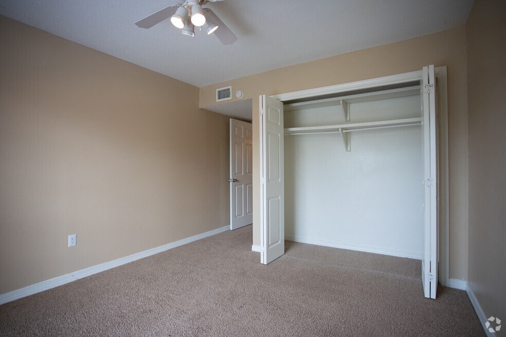 an empty bedroom with a closet and a ceiling fan