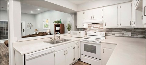 A white kitchen with a stove, sink, and cabinets.