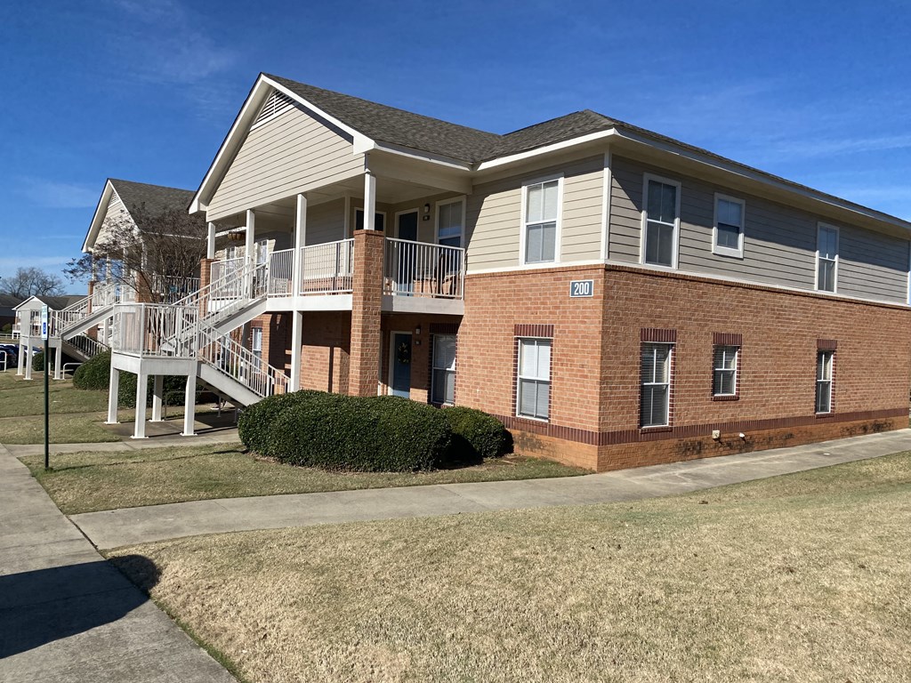 the front of a brick house with a porch and stairs