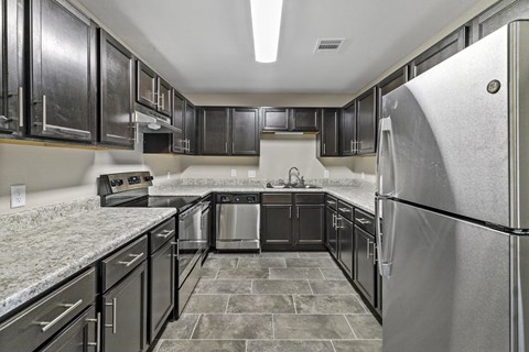 A kitchen with black cabinets and a granite counter top.