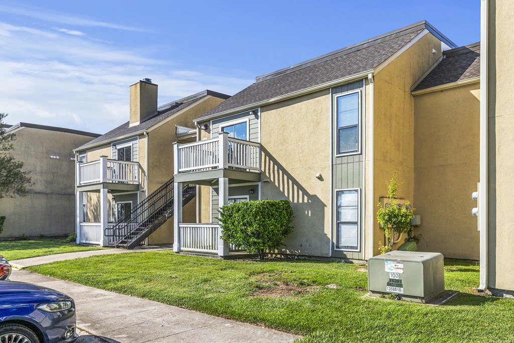 an apartment building with stairs and a yard with grass