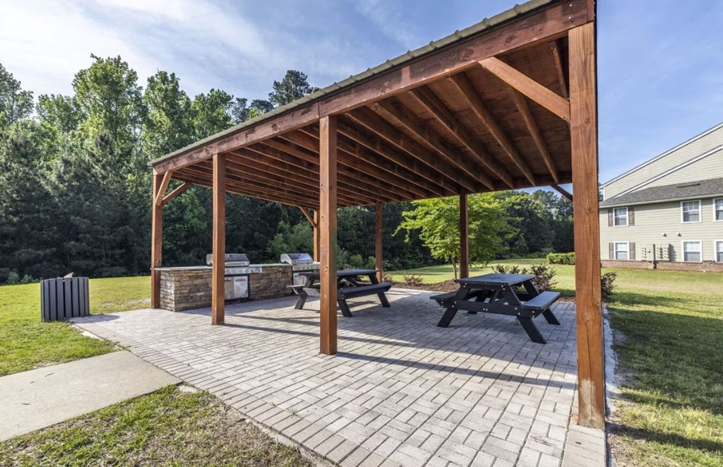 a wooden pavilion with picnic tables and a fire pit