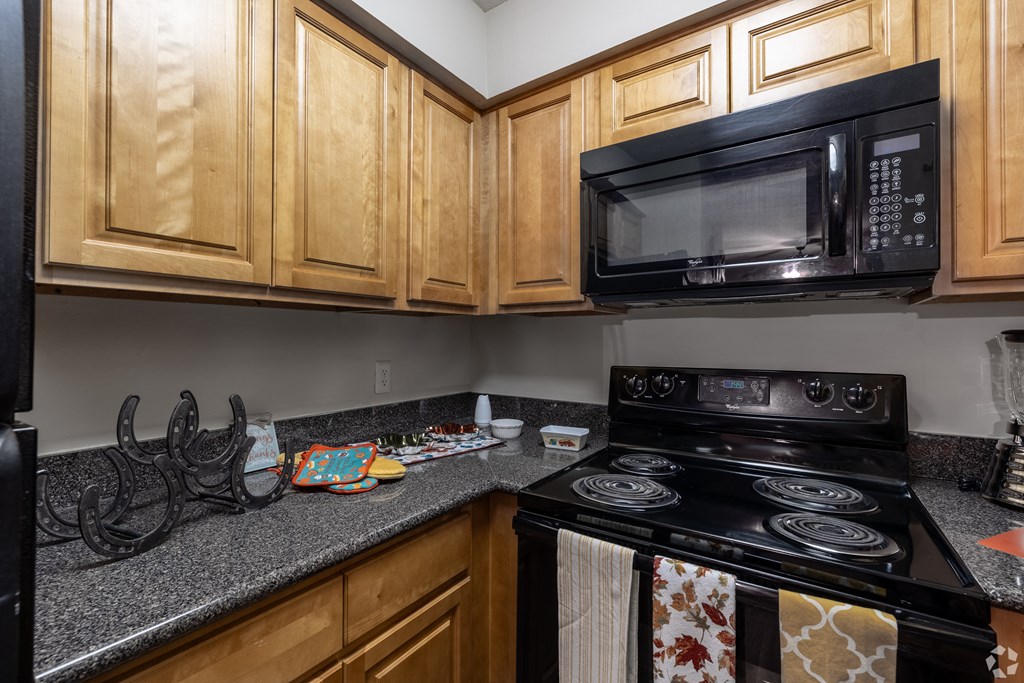 a kitchen with a stove and microwave and wooden cabinets