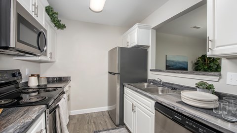 A kitchen with a black refrigerator and a black stove top oven.