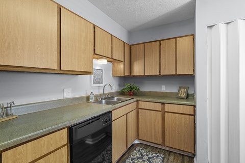 A kitchen with wooden cabinets and a black dishwasher.