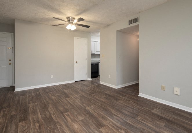 A room with a ceiling fan and wood flooring.
