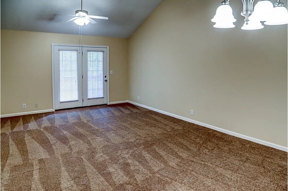 an empty living room with a door and a ceiling fan