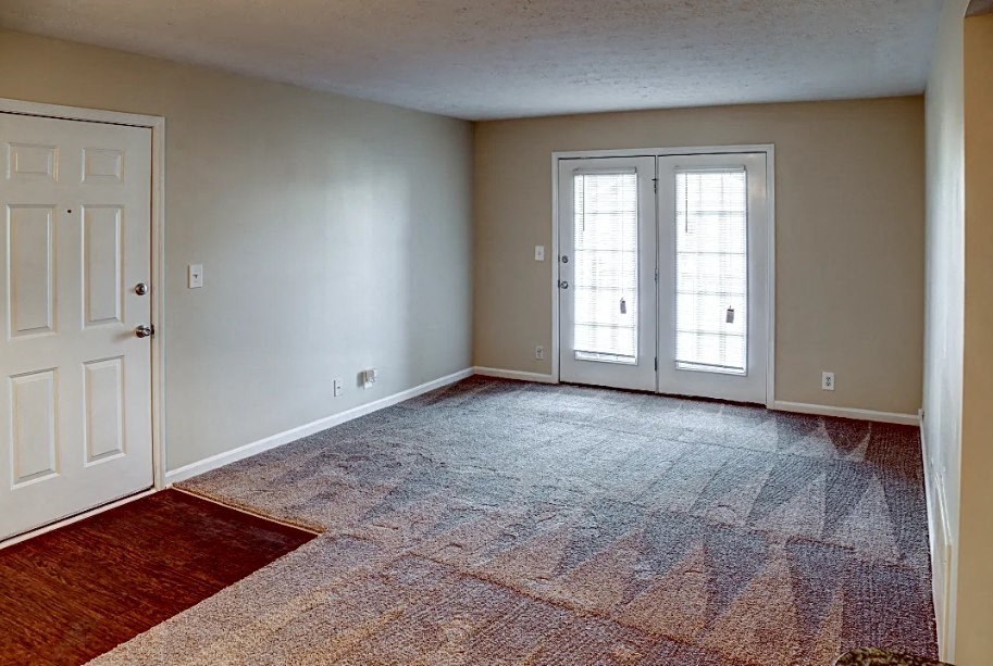 an empty living room with a door to a balcony