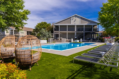 A large outdoor swimming pool with sun loungers and a building in the background.