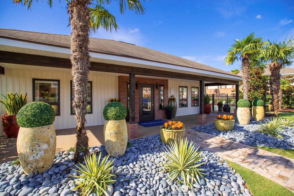 the front of a house with rocks and palm trees