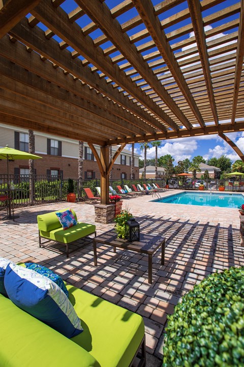 a swimming pool with lounge chairs under a wooden pavilion