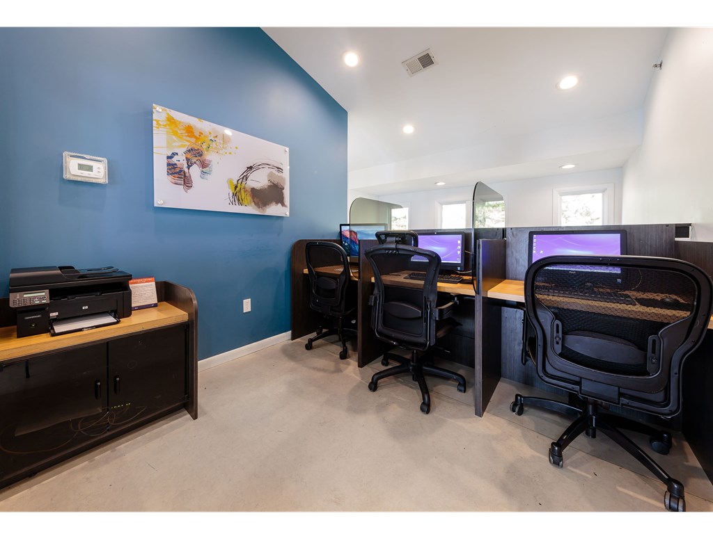 an office with four computers and a printer on a wooden desk